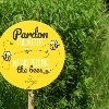 Yellow round sign with bees and the wording 'Pardon the weeds, we are feeding the bees'